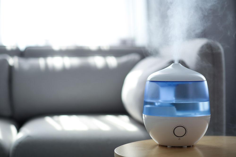 Humidifier sitting on coffee table blowing steam with sofa in the background