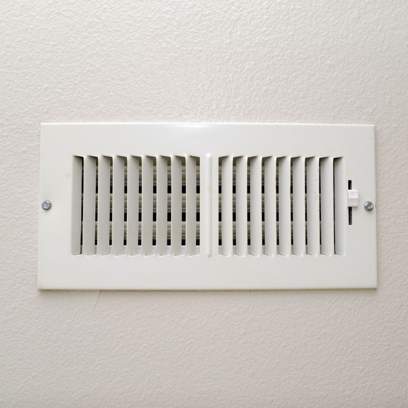 a white heating/cooling vent against a white wall